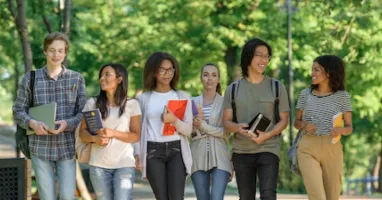 Gruppo di ragazzi e ragazze con libri in mano che camminano