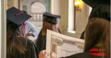 studentesse di spalle con toga e pergamena in mano
