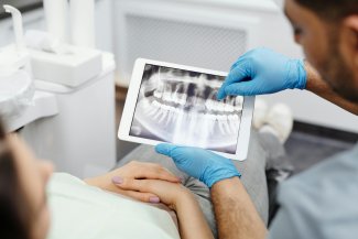 dentista che mostra lastra su tablet a paziente
