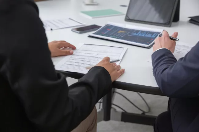 Ambiente professionale, probabilmente un ufficio o una sala riunioni, dove due persone sono impegnate in una consulenza o in un'attività di analisi finanziaria