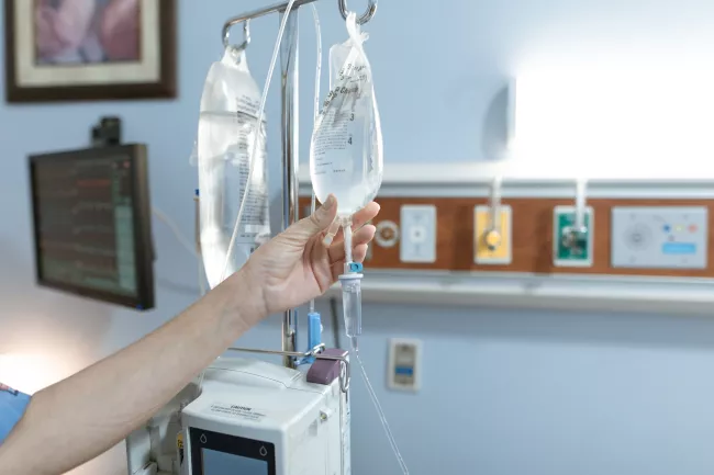 Mano di un operatore sanitario mentre tocca una sacca di liquido per infusione